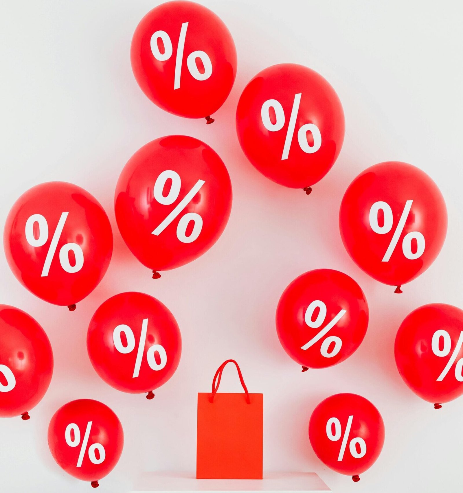 Red balloons with percentage symbols and a shopping bag on white background.