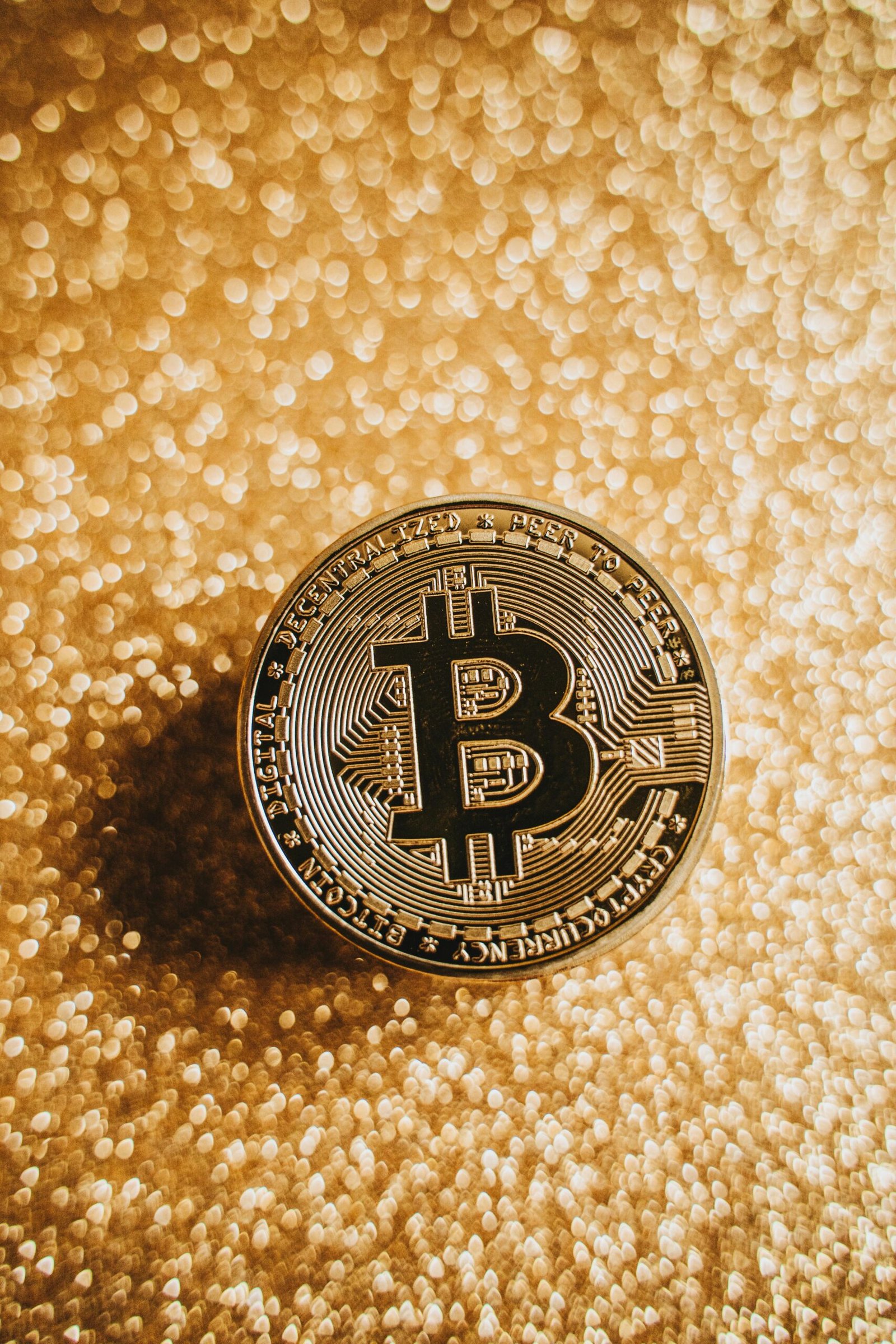 A close-up of a Bitcoin coin against a shimmering gold background, symbolizing digital currency and finance.