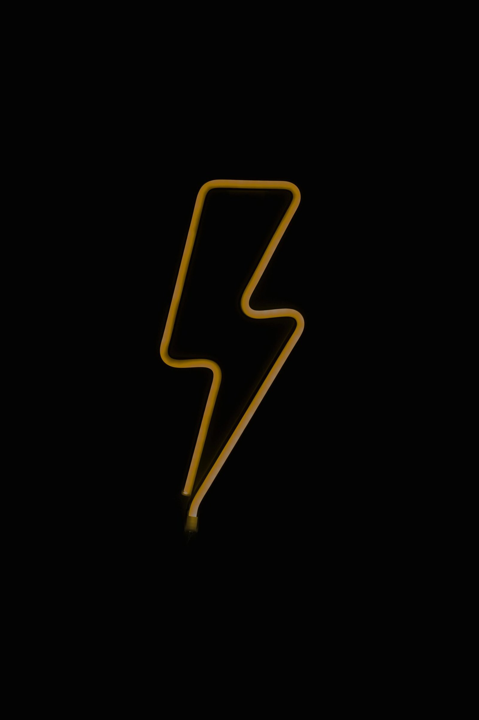 Bright yellow neon thunderbolt sign glowing on a dark black background, creating a striking visual contrast.